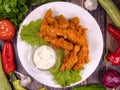 Tasty chicken bites with cornflakes in a plate, on a wooden table.