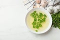 Tasty chicken bouillon in bowl and ingredients on white marble table, flat lay. Space for text Royalty Free Stock Photo
