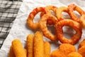 Tasty chicken nuggets, fried onion rings, cheese sticks and ketchup on parchment paper, closeup Royalty Free Stock Photo