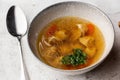 Tasty chicken soup bouillon with dumplings, chicken meat and parsley in a white bowl. Isolated on marble background Royalty Free Stock Photo