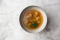 Tasty chicken soup bouillon with dumplings, chicken meat and parsley in a white bowl. Isolated on marble background Royalty Free Stock Photo