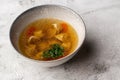 Tasty chicken soup bouillon with dumplings, chicken meat and parsley in a white bowl. Isolated on marble background Royalty Free Stock Photo