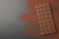 Tasty chocolate bar and cocoa powder on grey table, top view. Space for text Royalty Free Stock Photo