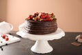 Tasty chocolate cake with strawberries and currants on table against color background Royalty Free Stock Photo