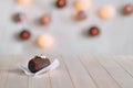 Tasty chocolate cake on a wooden natural background. Top decorated with cream and a piece of jelly. In the background glow round l