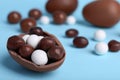 Tasty chocolate egg with different sweets inside on light blue background, closeup. Space for text Royalty Free Stock Photo