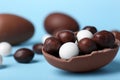 Tasty chocolate egg with different sweets inside on light blue background, closeup. Space for text Royalty Free Stock Photo