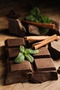 Tasty chocolate pieces, cinnamon sticks and mint on wooden table, closeup Royalty Free Stock Photo