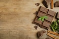 Tasty chocolate pieces, cinnamon sticks and mint on wooden table, flat lay. Space for text Royalty Free Stock Photo