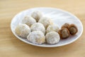 Christmas cookies, tasty balls with hazelnut inside and icing sugar, white plate and wooden table Royalty Free Stock Photo