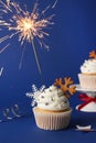 Tasty Christmas cupcake with snowflakes and burning sparkler on blue background Royalty Free Stock Photo