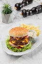 Tasty classic beef burger with french fries and sauce at the white plate on light marble background. Healthy sea food, hard light Royalty Free Stock Photo