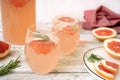 A tasty cocktail with grapefruit juice poured into glasses stands on a light wooden table. Royalty Free Stock Photo