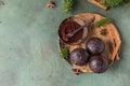 Tasty cocoa bombs with marshmallow and chocolate on wooden plate with fir branches and spices. Trendy winter hot drink. Top view