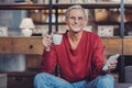 Emotional pensioner drinking coffee while dealing with bills