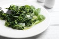 Tasty cooked spinach on white wooden table. Healthy food