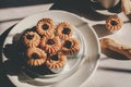 Tasty cookies with jam on top in white plates and hot coffee with window light.