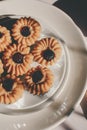 Tasty cookies with jam on top in white plates and hot coffee with window light.