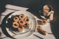 Tasty cookies with jam on top in white plates and hot coffee with window light.