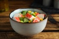 Tasty crab stick salad in bowl on wooden table, closeup