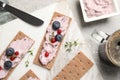 Tasty cracker sandwiches with cream cheese, blueberries, red currants, thyme and cup of coffee on grey table, flat lay Royalty Free Stock Photo