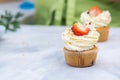 Tasty cream cheese cupcakes. Woman cooking cakes. Confectioner decorating cupcakes with strawberry. Cooking class, culinary and Royalty Free Stock Photo