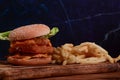 Tasty fish burger.and fried potatoes on wooden table. Royalty Free Stock Photo