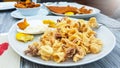 Tasty and crispy fried squids on a white plate and wooden table with mayonnaise sauce dropped with fresh lemon Royalty Free Stock Photo