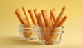 Tasty crispy sticks in glass cup on yellow background