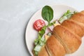 Tasty croissant sandwich with ham and cucumber on light grey marble table, top view Royalty Free Stock Photo