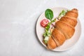 Tasty croissant sandwich with ham and cucumber on light grey marble table, top view. Space for text Royalty Free Stock Photo