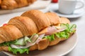 Tasty croissant sandwich with ham and cucumber on table, closeup Royalty Free Stock Photo