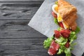 Tasty croissant sandwich with meat and egg on table Royalty Free Stock Photo