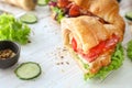 Tasty croissant sandwich with meat and fried egg on white wooden table Royalty Free Stock Photo