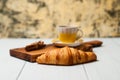 Tasty croissant and sweet coffee in yellow cup with cinnamon on a light background Royalty Free Stock Photo