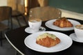 Tasty croissants and cups of aromatic coffee on black table in cafeteria Royalty Free Stock Photo