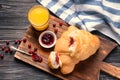 Tasty croissants with delicious jam and glass of orange juice on wooden board Royalty Free Stock Photo