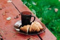 Tasty croissants with hot coffee on the bench