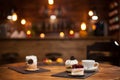 Tasty cup of coffee new delicious mini cakes with different shapes over a wooden table in a coffee shop Royalty Free Stock Photo
