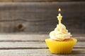 Tasty cupcake with candle on a grey wooden background
