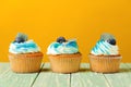 Tasty cupcakes with blueberry over yellow background. Birthday cupcakes for celebration. Cupcakes decorated with creamcheese and