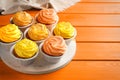 Tasty cupcakes on orange wooden table, space for text Royalty Free Stock Photo