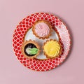 Tasty cupcakes on red pattern plate. Three different cupcakes with pink and yellow cream Royalty Free Stock Photo