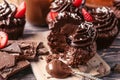 Tasty cupcakes with strawberry and pieces of chocolate bar on wooden table