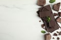 Tasty dark chocolate pieces with mint on white table, flat lay. Space for text Royalty Free Stock Photo