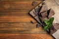 Tasty dark chocolate pieces with mint on wooden table, flat lay. Space for text Royalty Free Stock Photo