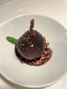 a tasty desert of a baked pear, pickled in red wine with strawberry sauce