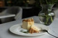 Tasty dessert and vase with flowers on white table in cafeteria