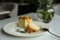 Tasty dessert and vase with flowers on white table in cafeteria