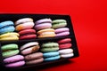 Tasty different colored macarons in black box on red background Royalty Free Stock Photo